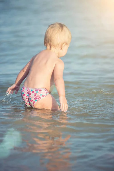 Niedliches Baby spielt am Sandstrand und im Meerwasser. — Stockfoto