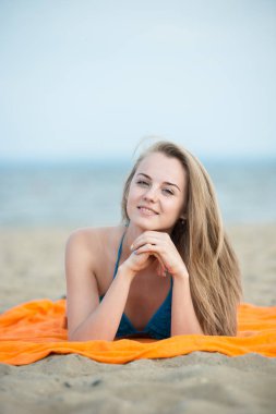 Kumsalda güneşlenirken genç bayan. Güzel kadın, poz