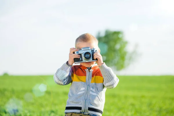 Kleiner Junge mit einer alten Kamera, die draußen schießt. — Stockfoto