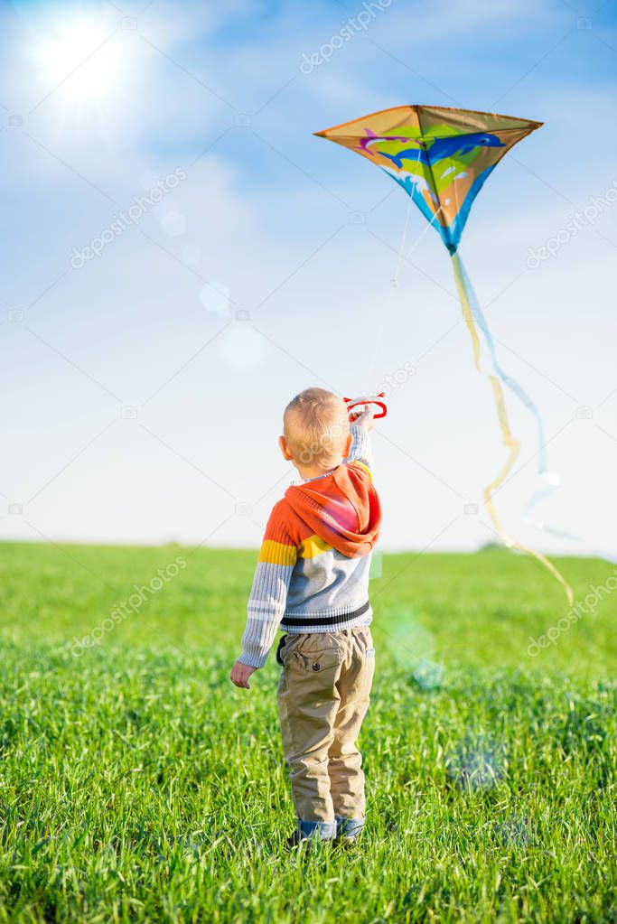 Young boy playing with his kite in a green field.