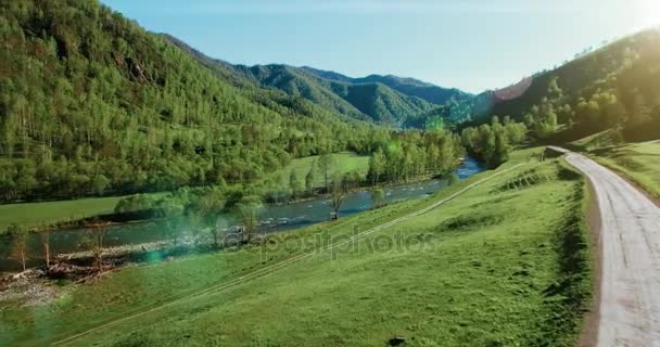 UHD 4k luchtfoto. Lage vlucht over verse koude berg rivier, weide en weg bij zonnige Zomerochtend. — Stockvideo