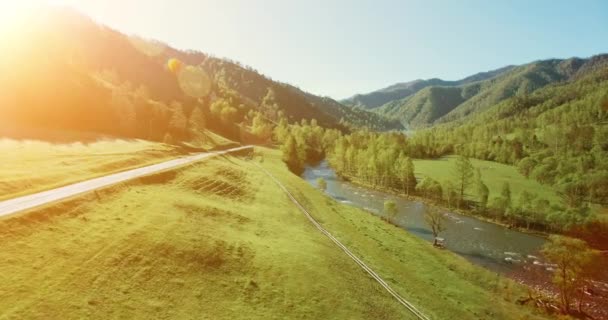 UHD 4K vista aérea. Vôo baixo sobre o rio frio fresco da montanha, o prado e a estrada na manhã ensolarada do verão . — Vídeo de Stock