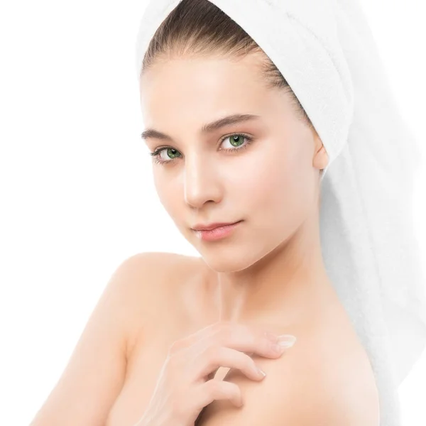 Mulher com rosto limpo e toalha na cabeça aplicando creme hidratante nos ombros. Isolados . — Fotografia de Stock
