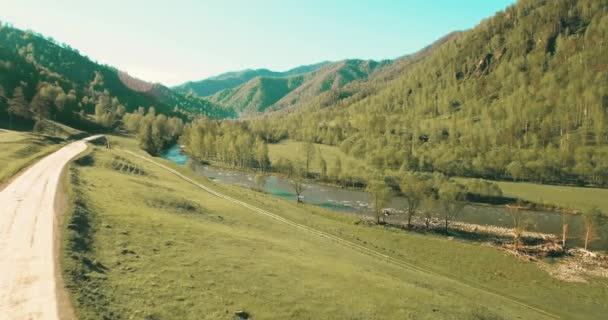 UHD 4K aerial view. Low flight over fresh cold mountain river, meadow and road at sunny summer morning. — Stock Video