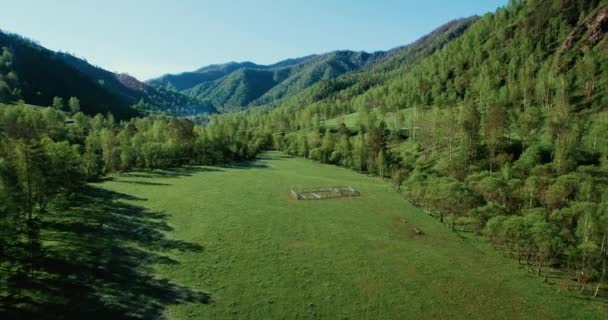 UHD 4K vista aérea. Vuelo bajo sobre el río fresco y frío de la montaña, prado y carretera en la soleada mañana de verano . — Vídeo de stock