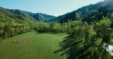 UHD 4k havadan görünümü. Düşük uçuş taze soğuk dağ nehir, çayır ve yola güneşli yaz sabahı.