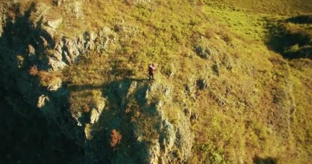 Orbitális sugárirányú repülés körül gyalogos fiatalember, egy szikla tetején áll. Úgy néz ki, el. — Stock videók