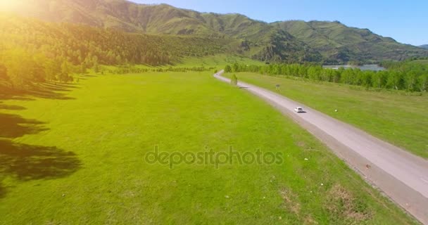 Flight over cars on a winding road in the hills and meadow. Rural highway below. — Stock Video