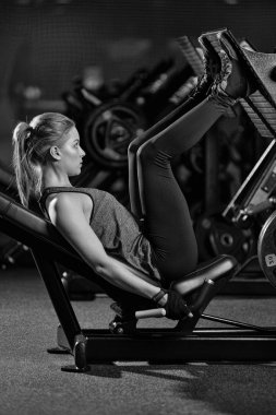 Bacaklar için ağırlıklar basın makine kullanan sportif kadın. Spor salonu.