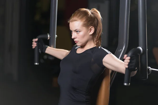 Woman at the sport gym doing arms exercises on a machine — Stock Photo, Image