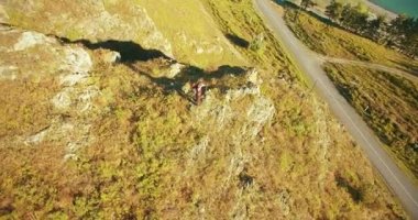 Genç yürüyüş adam uçurumun üstünde ayakta çevresinde yörünge Radyal uçuş. Uzakta görünüyor.