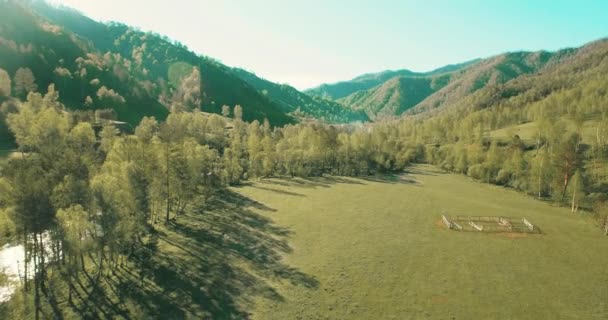 UHD 4K vista aérea. Vuelo bajo sobre el río fresco y frío de la montaña, prado y carretera en la soleada mañana de verano . — Vídeo de stock
