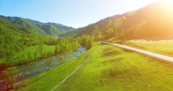 UHD 4K vista aérea. Vôo baixo sobre o rio frio fresco da montanha, o prado e a estrada na manhã ensolarada do verão . — Vídeo de Stock