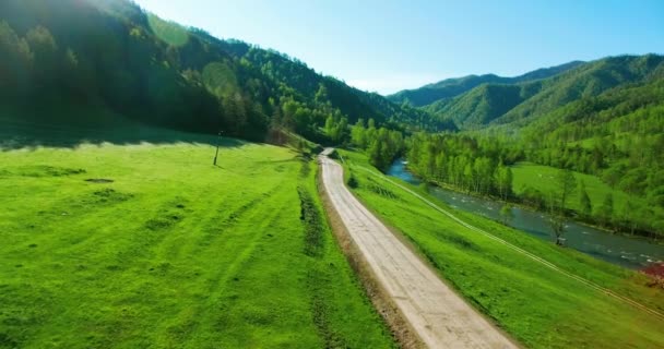 Vista aérea UHD 4K. Vuelo aéreo bajo sobre la montaña, camino de tierra rural y prado . — Vídeo de stock