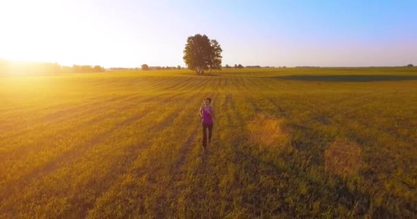 UHD 4K vista aérea. Vuelo de baja altitud frente a una mujer deportiva en el campo rural — Vídeo de stock