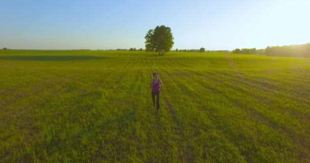 UHD 4K vista aérea. Vuelo de baja altitud frente a una mujer deportiva en el campo rural — Vídeo de stock