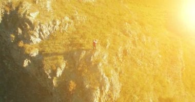 Genç yürüyüş adam uçurumun üstünde ayakta çevresinde yörünge Radyal uçuş. Uzakta görünüyor.