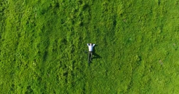 Vol vertical au-dessus d'un homme d'affaires allongé sur un pré vert frais. Vue de dessus sur homme relaxant .