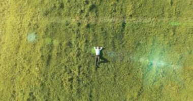 Taze yeşil çayır üzerinde yalan işadamı üzerinde dikey hareket uçuş. Üstten Görünüm üzerinde rahatlatıcı dostum.