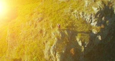 Genç yürüyüş adam uçurumun üstünde ayakta çevresinde yörünge Radyal uçuş. Uzakta görünüyor.