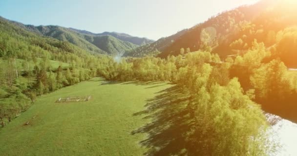 Voo no meio do ar sobre o rio e o prado da montanha fresca na ensolarada manhã de verão. Estrada de terra rural abaixo . — Vídeo de Stock