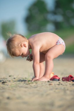 Şirin Bebek denize yakın kum plajındaki oyuncaklar ile oynama.