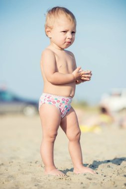 Şirin Bebek denize yakın kum plajındaki oyuncaklar ile oynama.