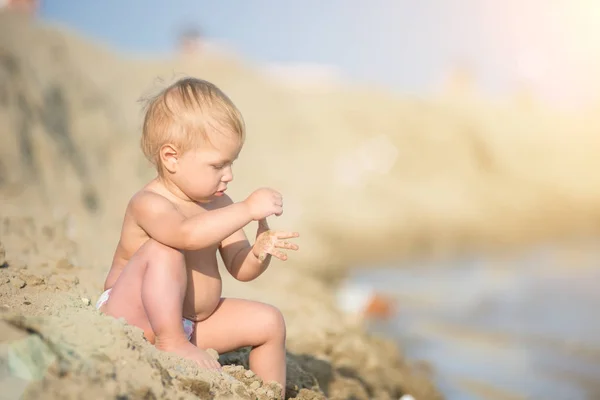Lindo bebé jugando con juguetes en la playa de arena cerca del mar . —  Fotos de Stock