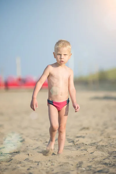 Carino il bambino che cammina sulla spiaggia sabbiosa vicino al mare. Costa oceanica . — Foto Stock