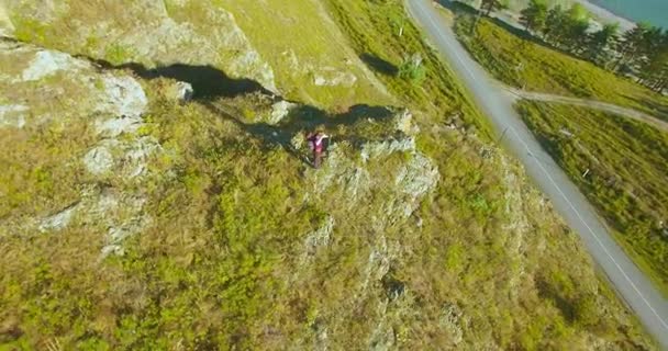 Orbitalradialflug um den jungen Wanderer herum, der oben auf der Klippe steht. Wegschauen. — Stockvideo