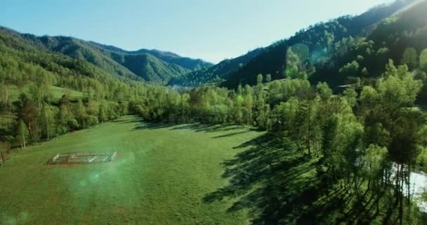 UHD 4K vista aérea. Vuelo bajo sobre el río fresco y frío de la montaña, prado y carretera en la soleada mañana de verano . — Vídeo de stock