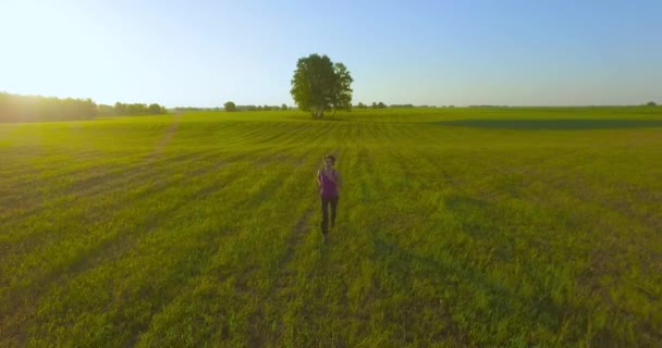 UHD 4K aerial view. Low altitude flight in front of sporty woman at rural field — Stock Video