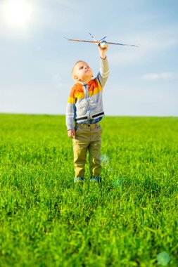 Oyuncak uçak mavi yaz gökyüzü ve yeşil alan arka plan karşı oynamaktan mutlu çocuk.