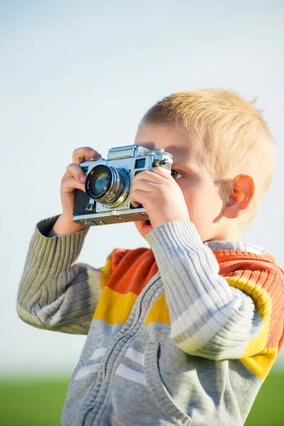 Kleine jongen met een oude camera schieten buiten. — Stockfoto