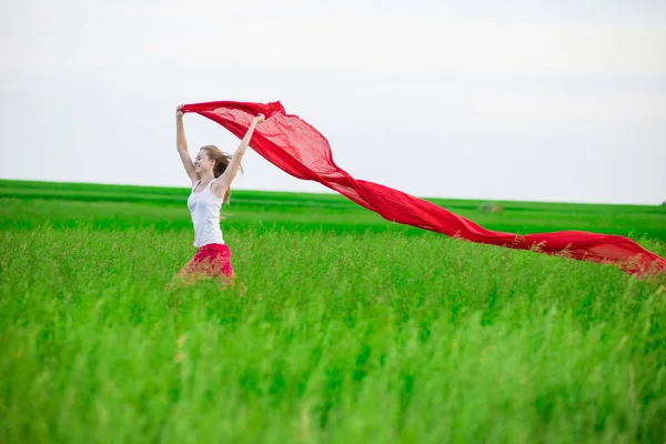 Young lady runing with tissue in green field. Woman with scarf. — Stock Photo, Image