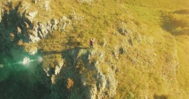 Genç yürüyüş adam uçurumun üstünde ayakta çevresinde yörünge Radyal uçuş. Uzakta görünüyor.