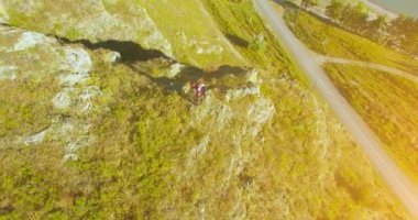 Genç yürüyüş adam uçurumun üstünde ayakta çevresinde yörünge Radyal uçuş. Uzakta görünüyor.