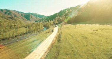 Havadan Uhd 4k görünümü. Düşük hava uçuş dağ kırsal toprak yol ve güneşli yaz sabahı, çayır üzerinde