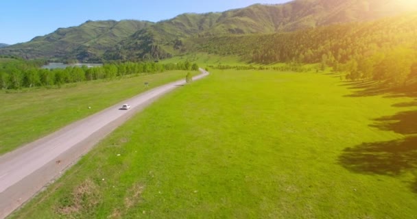 Flight over cars on a winding road in the hills and meadow. Rural highway below. — Stock Video