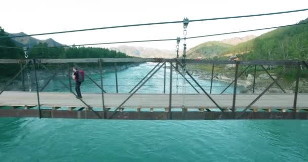 Midden in de lucht vlucht over jongeman toeristische wandeling over een hangbrug. — Stockvideo