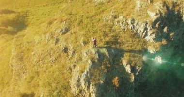 Genç yürüyüş adam uçurumun üstünde ayakta çevresinde yörünge Radyal uçuş. Uzakta görünüyor.