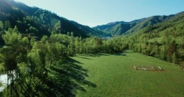 UHD 4k havadan görünümü. Düşük uçuş taze soğuk dağ nehir, çayır ve yola güneşli yaz sabahı.