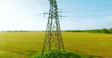 Yüksek voltajlı elektrik kulesi ve yeşil ve sarı alandaki elektrik hatları yakınında dikey hareket.