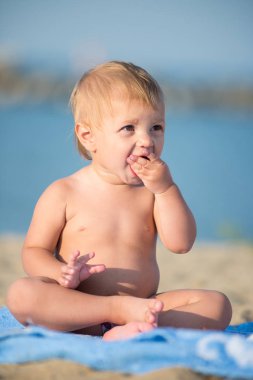Şirin Bebek denize yakın kum plajındaki oyuncaklar ile oynama.