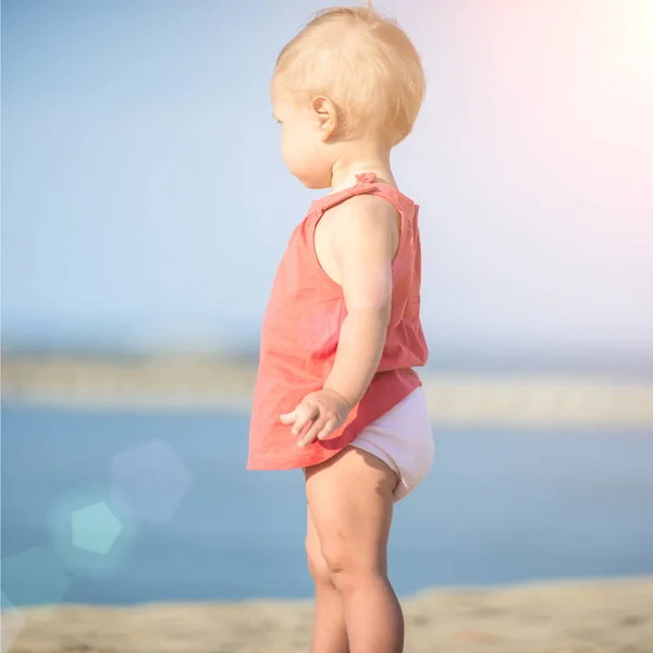 바다 근처의 모래 해변에 빨간 드레스에 여자 아기. — 스톡 사진