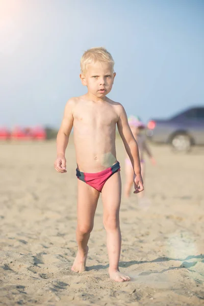 Carino il bambino che cammina sulla spiaggia sabbiosa vicino al mare. Costa oceanica . — Foto Stock