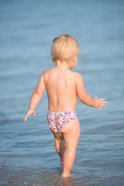 Niedliches Baby spielt am Sandstrand und im Meerwasser. — Stockfoto