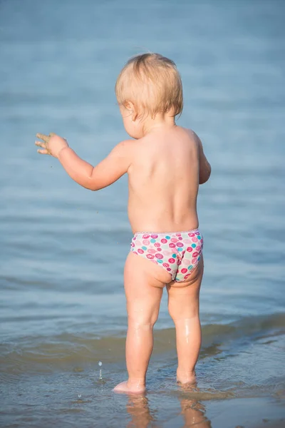 Carino bambino che gioca sulla spiaggia di sabbia e in acqua di mare . — Foto Stock