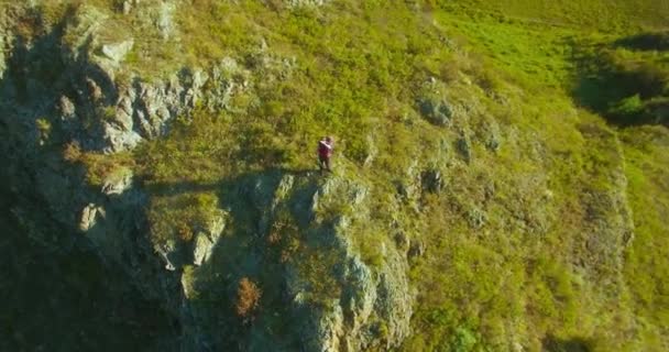 Orbitalradialflug um den jungen Wanderer herum, der oben auf der Klippe steht. Wegschauen. — Stockvideo