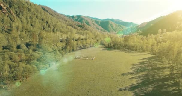 Vista aerea UHD 4K. Basso volo sul fresco fiume di montagna freddo, prato e strada al sole mattina d'estate . — Video Stock